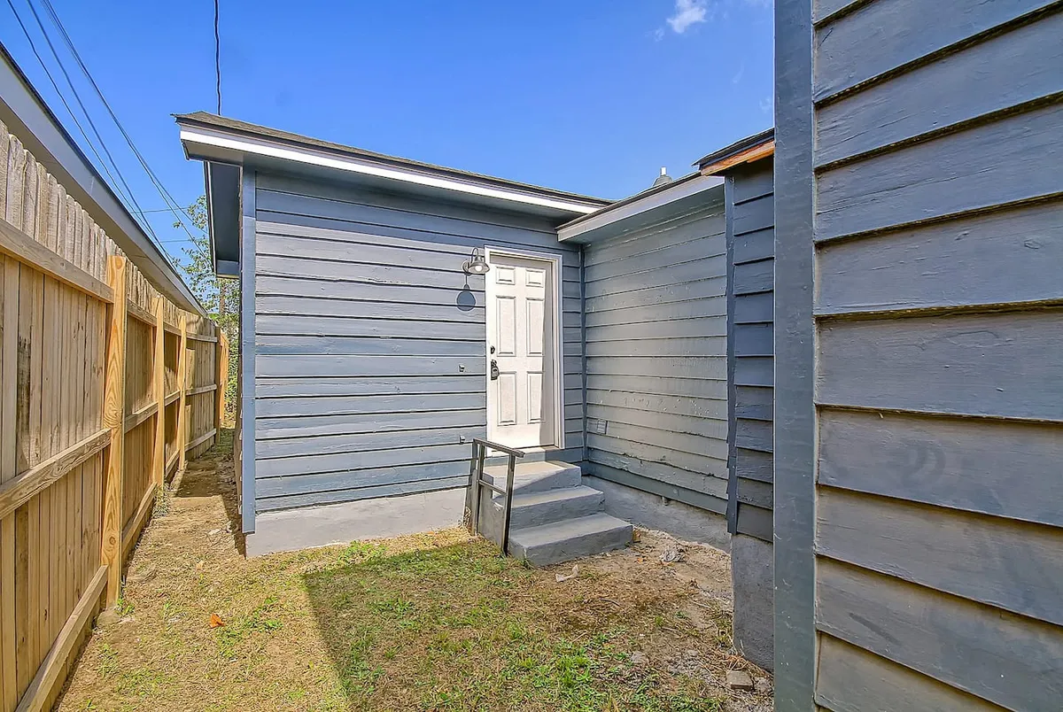 The front door with steps leading up, surrounded by blue siding. The scene is lively and welcoming, hinting at gatherings, chats on the steps, and group comings-and-goings.